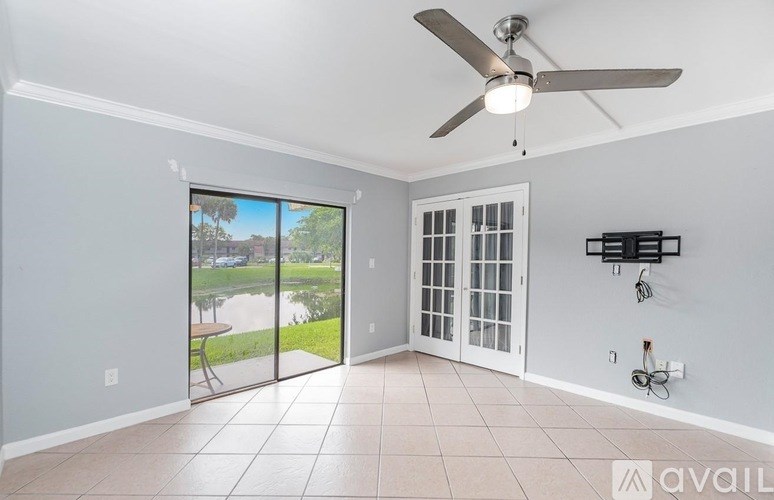 A room with a ceiling fan and sliding glass doors leading to a patio.