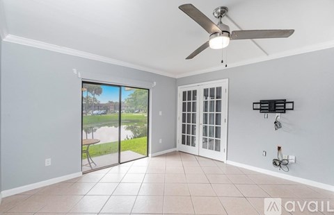 A room with a ceiling fan and sliding glass doors leading to a patio.