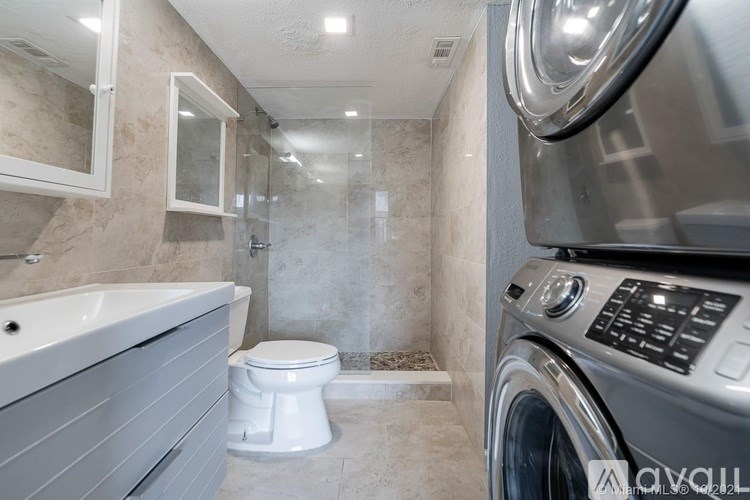 A modern bathroom with a washer and dryer built into the cabinetry.