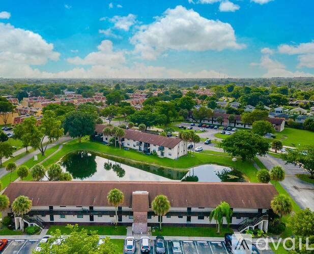 A bird's eye view of a residential area with a large building in the foreground and a lake in the middle.