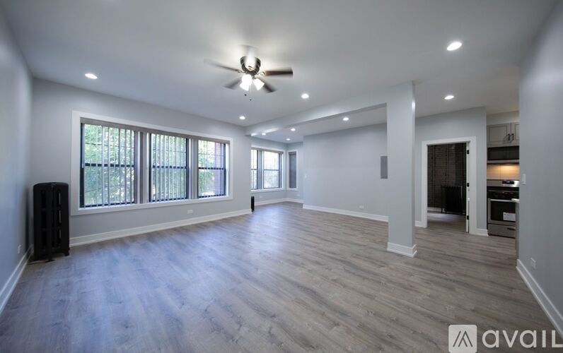 A spacious room with a ceiling fan and wooden flooring.