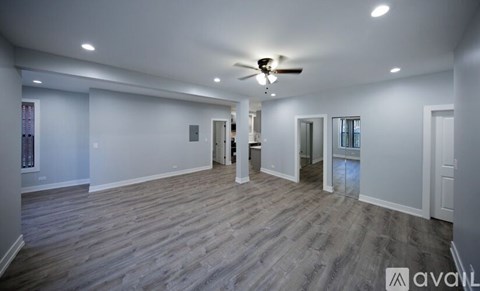 A spacious room with wooden flooring and a ceiling fan.
