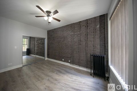 A room with a ceiling fan and a brick wall.