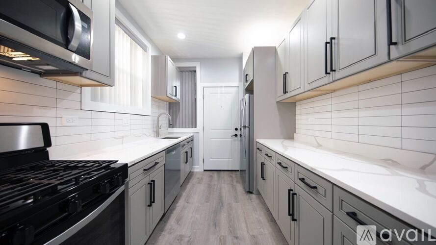 A modern kitchen with a black stove top and white tiled backsplash.