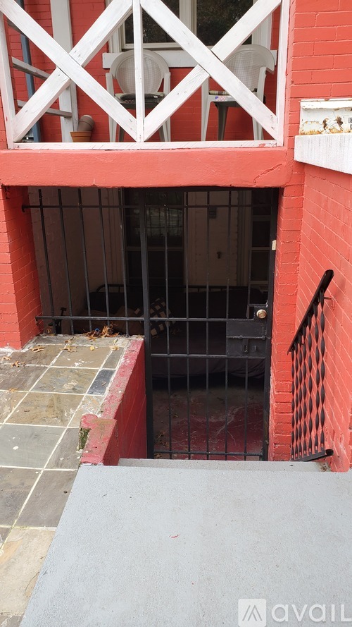 A red building with a white balcony and a black gate.