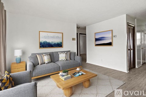A living room with a grey couch, a wooden coffee table, and two framed pictures on the wall.