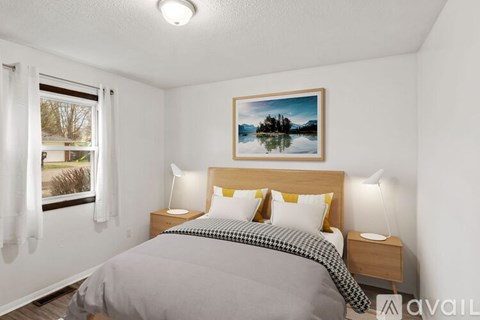A bedroom with a bed, nightstands, and a painting of a lake.