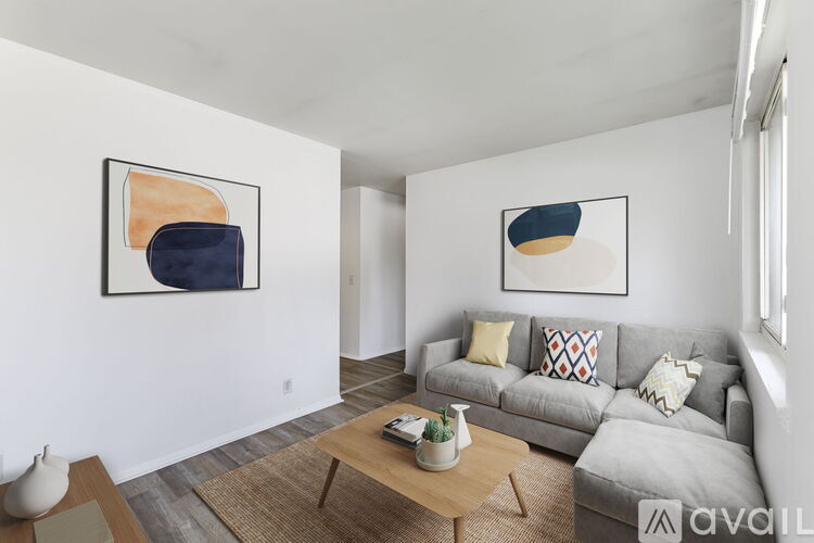 A living room with a grey couch and two abstract paintings on the wall.