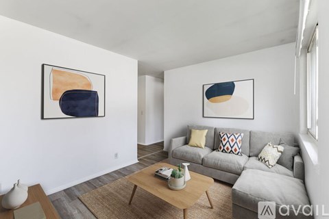 A living room with a grey couch and two abstract paintings on the wall.