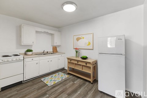 A kitchen with white appliances and wooden flooring.