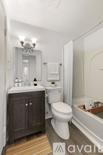 A bathroom with a toilet, sink, and mirror.