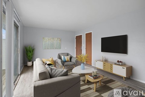 A living room with a grey couch, a wooden coffee table, and a flat-screen TV mounted on the wall.