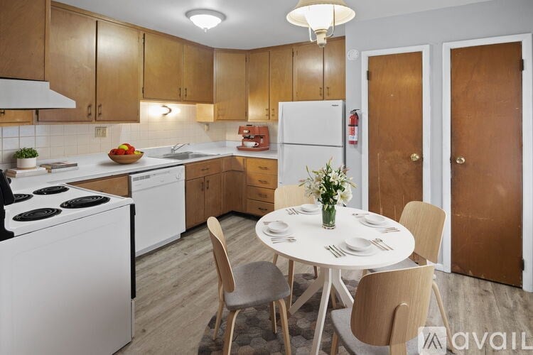 A kitchen with a table set for two and a vase of flowers on the table.