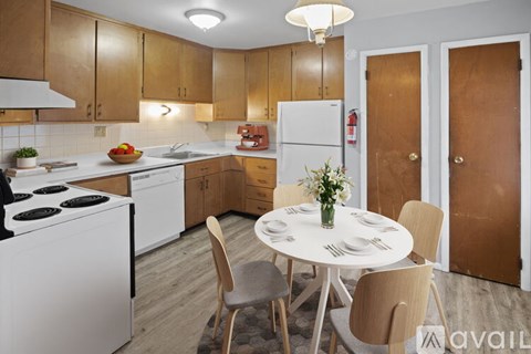 A kitchen with a table set for two and a vase of flowers on the table.