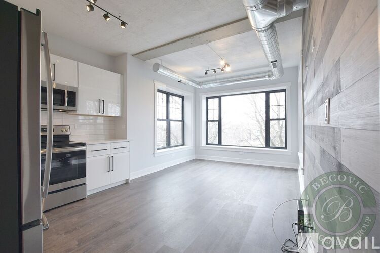 A spacious kitchen with white cabinets and a stainless steel refrigerator.