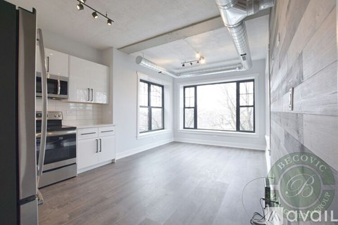 A spacious kitchen with white cabinets and a stainless steel refrigerator.