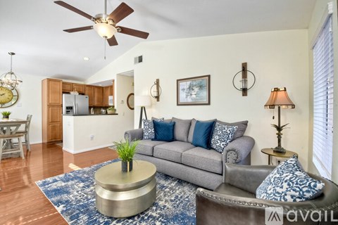 A living room with a grey couch, a round coffee table, and a ceiling fan.