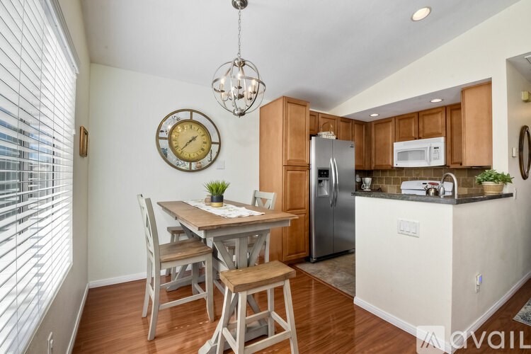A kitchen with a table and chairs and a clock on the wall.