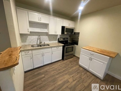 A kitchen with white cabinets and a wooden countertop.