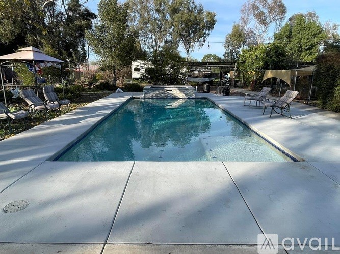 A pool surrounded by trees and chairs.