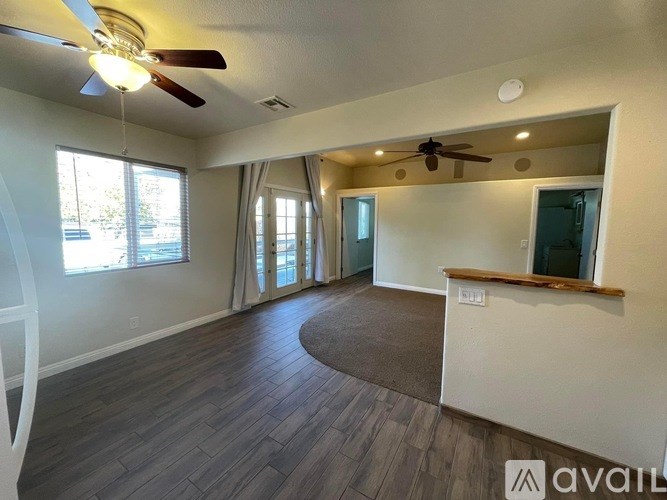 A spacious living room with a ceiling fan and sliding glass doors.