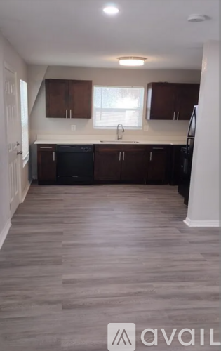 A kitchen with wooden floors and dark cabinets.