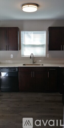 A kitchen with dark brown cabinets and a black dishwasher.