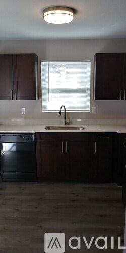A kitchen with dark brown cabinets and a black dishwasher.