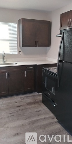 A kitchen with brown cabinets and a black refrigerator.