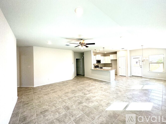 A spacious living room with a ceiling fan and tiled flooring.