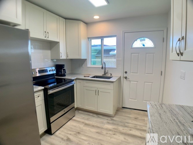 A kitchen with white cabinets and a stainless steel refrigerator.