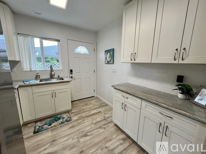 A kitchen with white cabinets and a wooden floor.