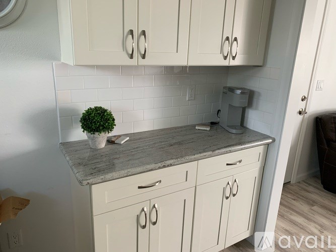 A kitchen with white cabinets and a marble countertop.
