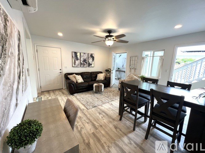 A living room with a black couch and a dining table with chairs.
