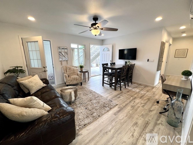 A living room with a brown leather couch and a ceiling fan.