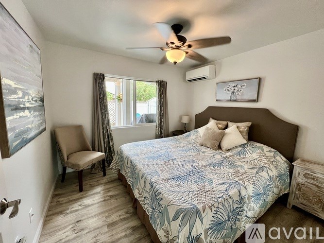 A bedroom with a bed, chair, and ceiling fan.