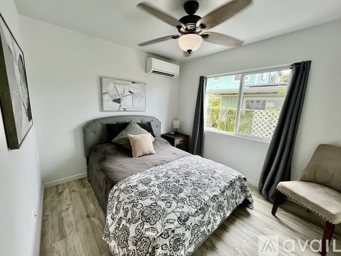 A bedroom with a bed, chair, and window.