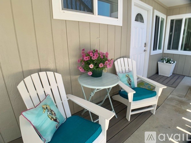 A white chair with a blue cushion is placed on a wooden deck.