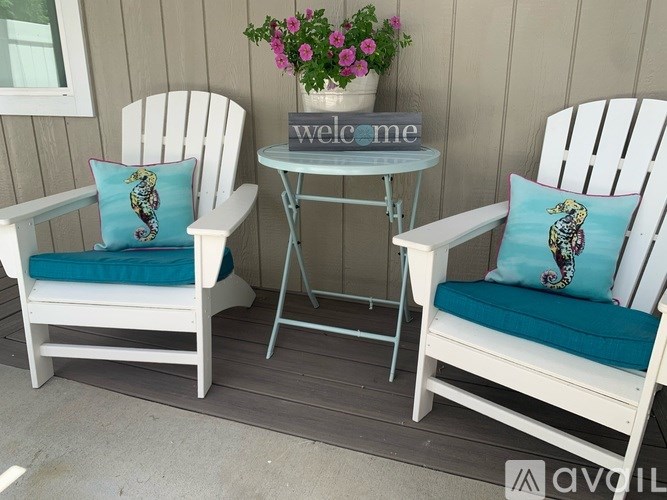 Two white chairs with blue cushions and a table with a "welcome" sign.