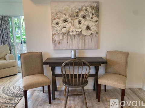 A dining room with a table, chairs and a painting on the wall.
