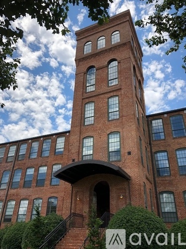 A tall red brick building with a tower and a balcony.