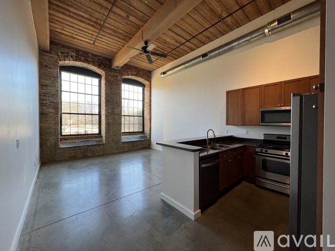 A spacious kitchen with a brick wall and a ceiling fan.