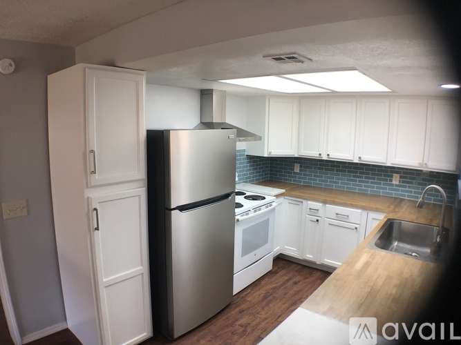 A kitchen with white cabinets and a stainless steel refrigerator.