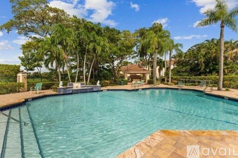 A swimming pool surrounded by palm trees and a house in the background.