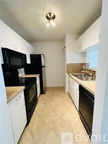 A kitchen with black and white appliances and a tiled floor.