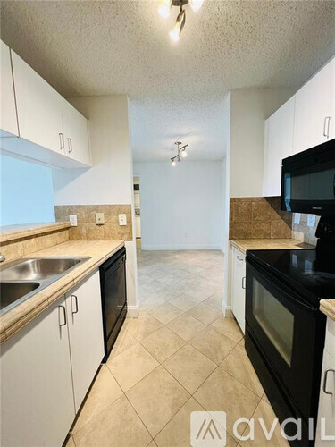 A kitchen with black appliances and white cabinets.