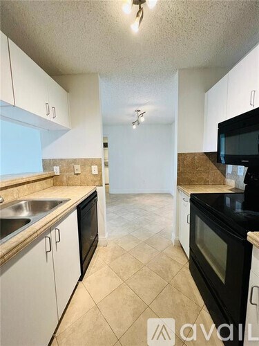 A kitchen with black appliances and white cabinets.