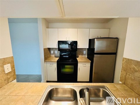 A kitchen with a black stove top oven, a black microwave, and a black refrigerator.