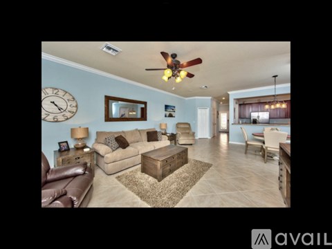 A living room with a brown leather couch and a ceiling fan.
