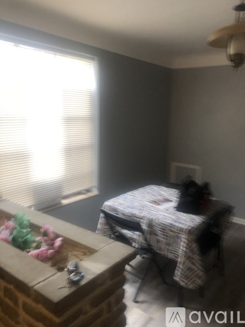 A cat is sitting on a bed in a room with a window and a fan.
